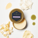 Picture of Nourishing Hand Balm in gold tin surrounded by shea butter, beeswax, tamanu oil, and essential oil