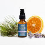 Picture of Moisturizing Hand Sanitizer in amber bottle with black spray cap filled with our moisturizing hand sanitizer blend surrounded by a fresh half orange, pine leaves, and lavender buds