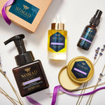 Nomad Botanicals Wild Mistral Deluxe Collection including the Revitalizing Body Oil, Foaming Hand Wash, Nourishing Hand Balm, and Moisturizing Hand Purifier with a ribbon wrapped gift box