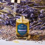 Nomad Botanicals Wild Mistral Revitalizing Body Oil surrounded by lavender buds